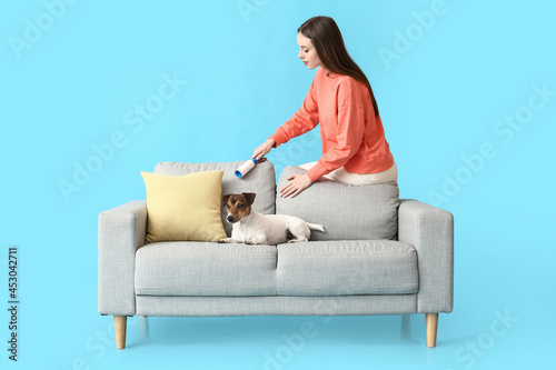 Young woman cleaning sofa w...