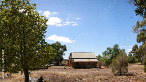 Panoramic view of a broken decaying old timber farmers workers home surrrounded by native trees on a dry barron agricultural property, rural Victoria, Australia