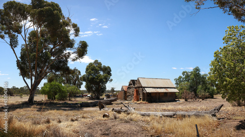 Panoramic view of a broken decaying old timber farmers workers home surrrounded by native trees on a dry barron agricultural property, rural Victoria, Australia photo