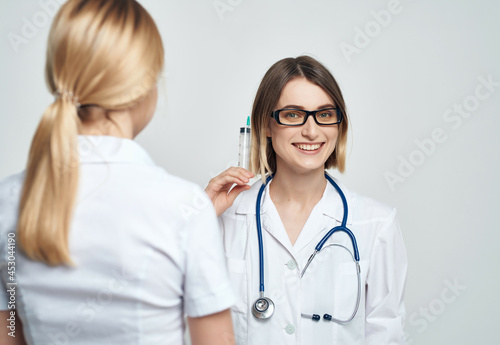 female doctor syringe in hand treatment light background