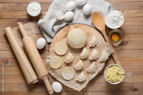 Composition with raw dumplings on wooden background