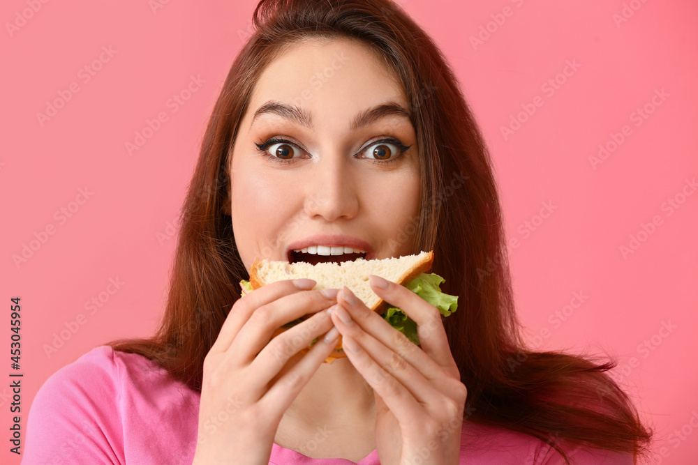Young woman eating tasty sandwich on color background Young woman eating tasty sandwich on color background