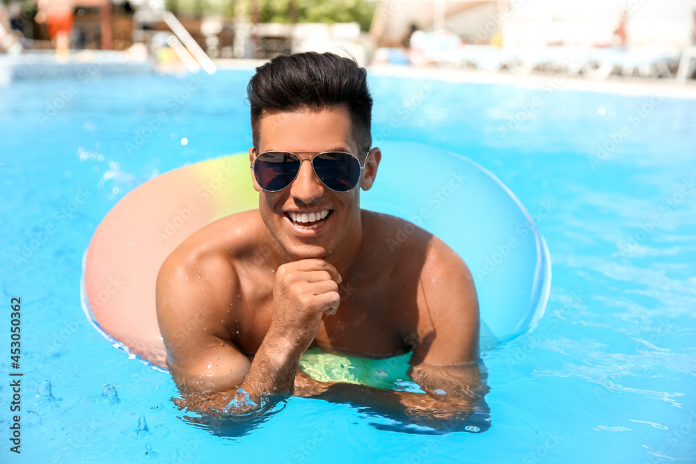 Young man with inflatable ring in swimming pool