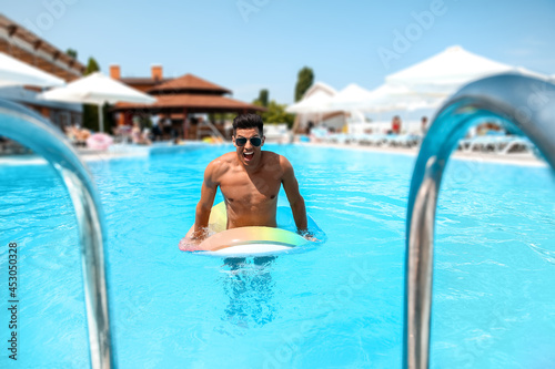 Young man with inflatable ring in swimming pool © Pixel-Shot