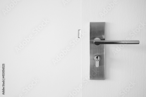 Modern door handle with keyhole on white door photo
