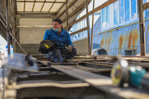 Semi-trailer repair. A mechanic repairs a trailer with a welding machine.