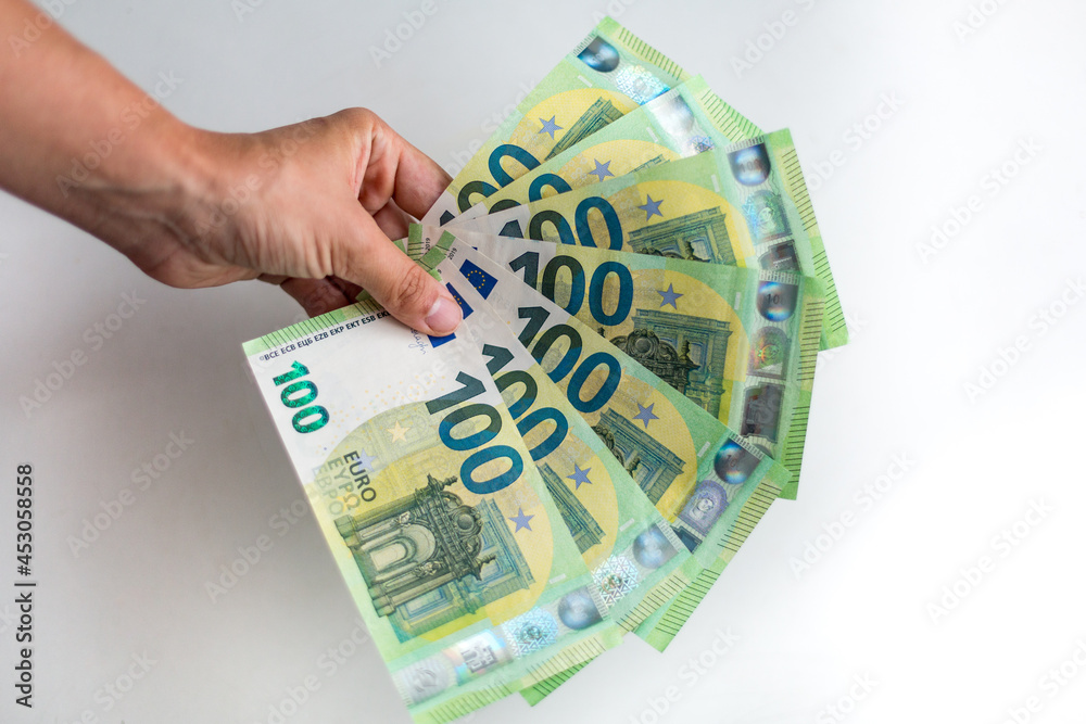Male hand holds European money Euro on white background: 100 euro currency banknotes. Inflation, business, economics and finance theme. - obrazy, fototapety, plakaty 