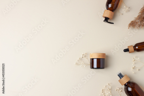 Cosmetic skin care products with flowers and pampas on pastel beige background. Flat lay, copy space