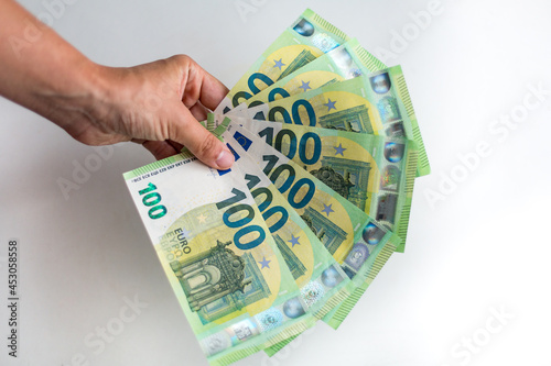 Male hand holds European money Euro on white background: 100 euro currency banknotes. Inflation, business, economics and finance theme.
