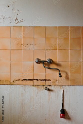 Old abandoned kitchen interior with a tap and tiles