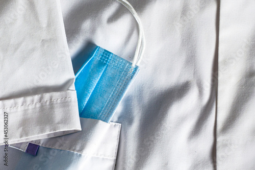 blue protective medical mask in the side pocket of a white medical coat
