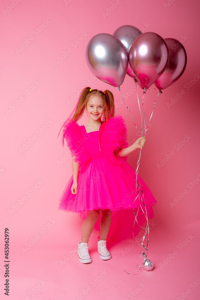 little girl on a pink background holding balloons, celebrating her birthday