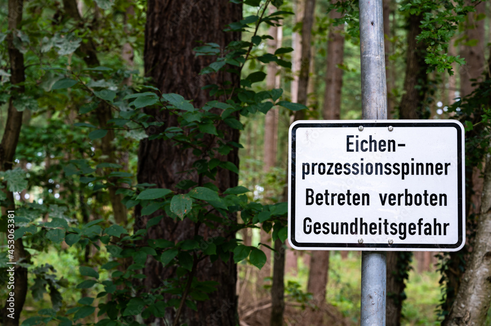 Ein Schild warnt vor dem gefährlichen Eichenprozessionsspinner am Waldrand