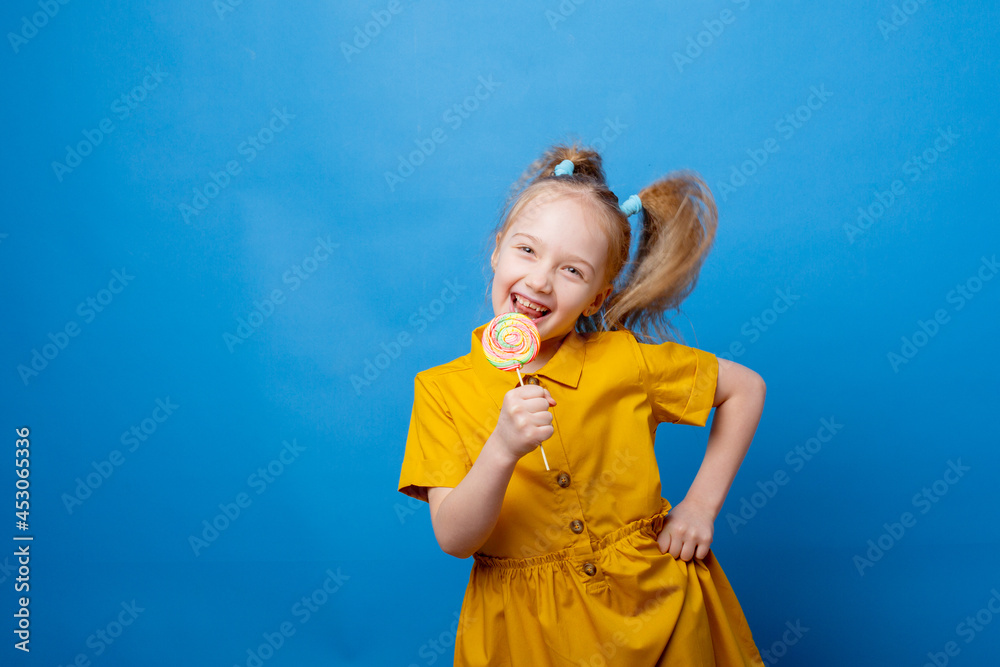 little girl holds a lollipop on a blue background little girl holds a lollipop on a blue background