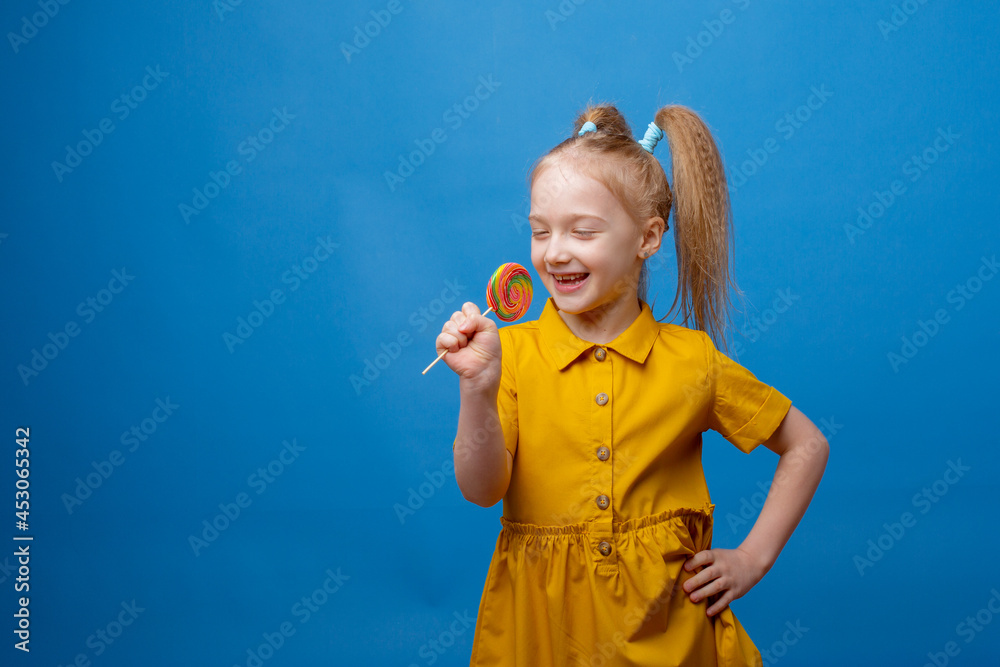 little girl holds a lollipop on a blue background little girl holds a lollipop on a blue background
