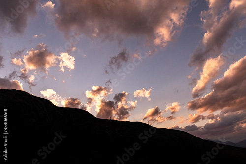 ciel pendant un coucher de soleil avec une femme en silhoutette dans les montagnes du parc naturel regional de l'Ubaye dans les alpes francaises.