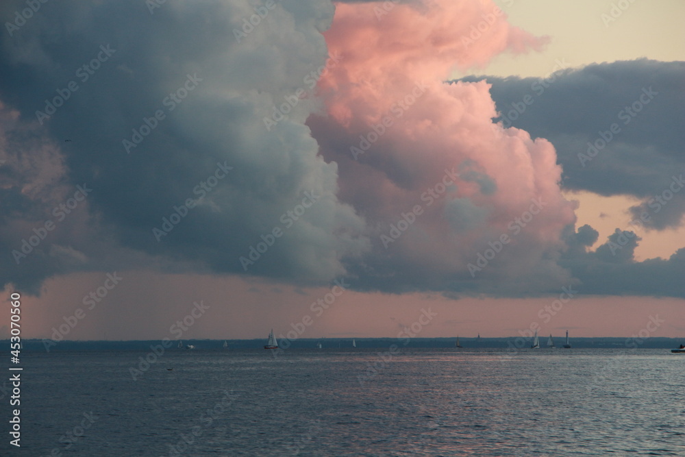 Clouds at sunset, the sea and sailboats