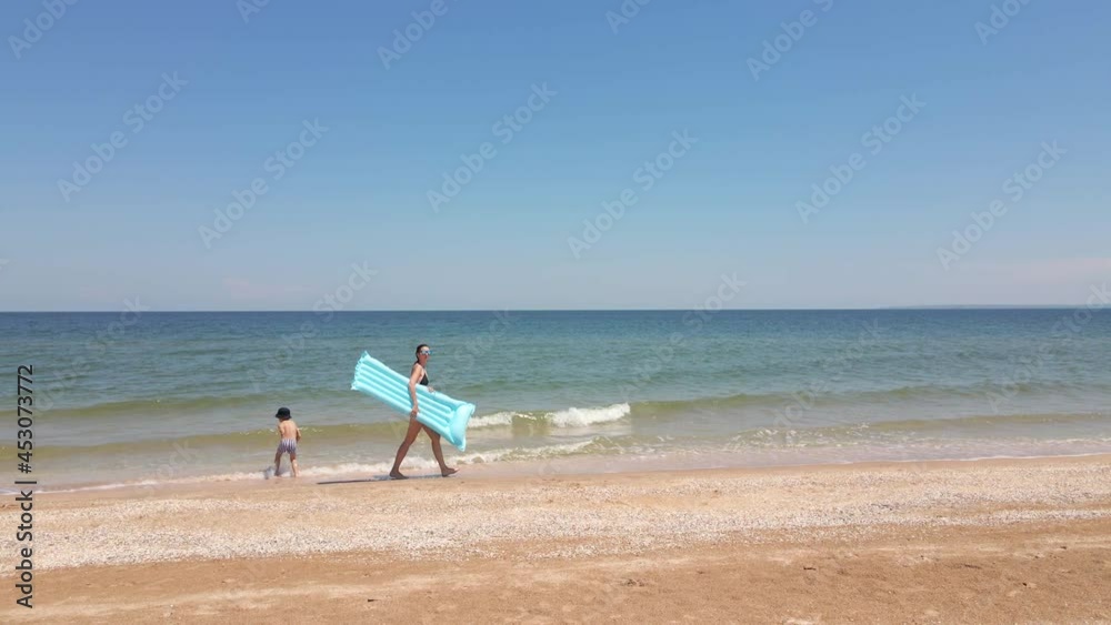 woman in a swimsuit walks along the beach by the sea woman in a swimsuit walks along the beach by the sea