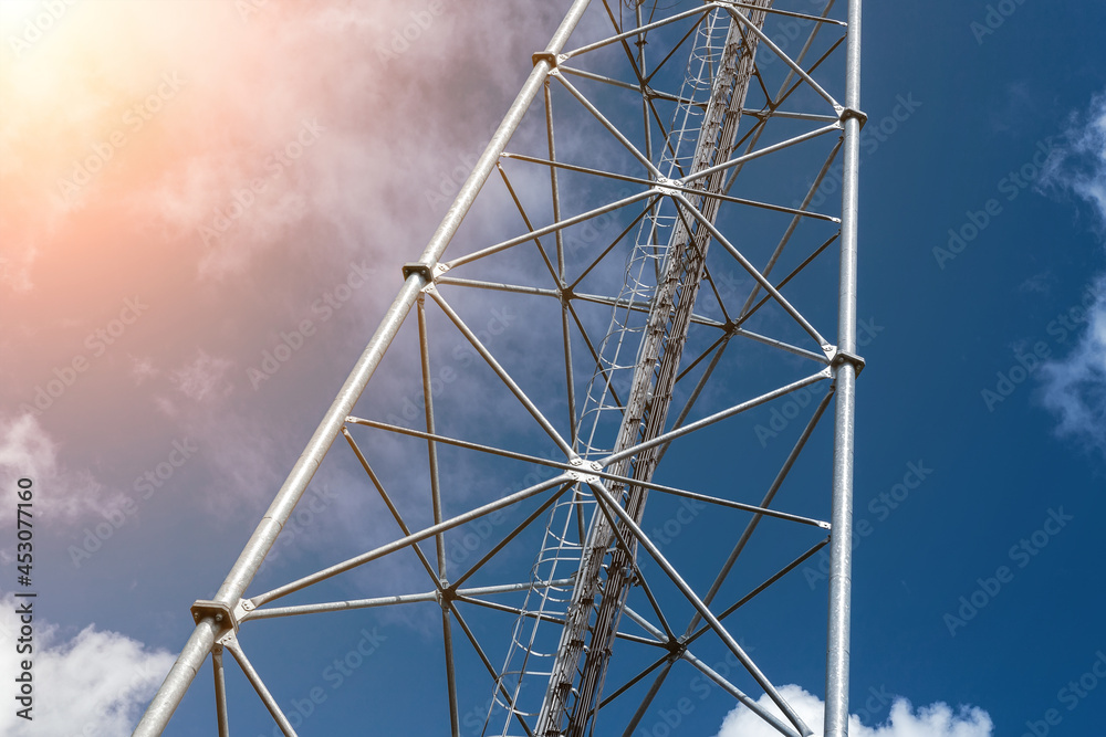 Bottom perspective pov of modern metal steel mobile 5g network wireless telecom tower against clear blue sky background on bright day. Microwave signal broadband equipment base line station mast