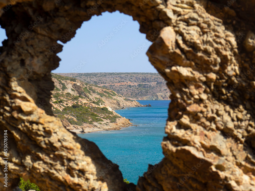 A hole in the rock with a view of the beach