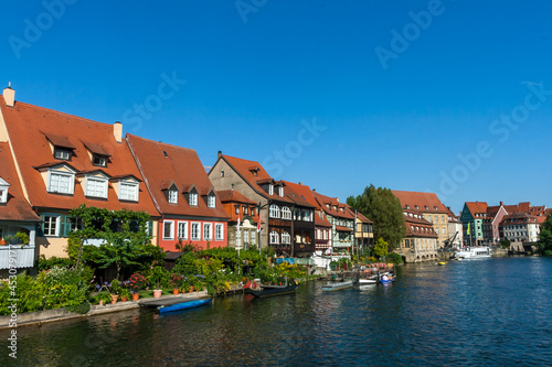 Bamberg Germany 08-08-2019 - Picturesque view of the medieval buildings along the Regnitz River with old barge, moored boats and on the river shore in UNESCO Heritage city Bamberg, Bavaria, Germany. © Prashanth Bala