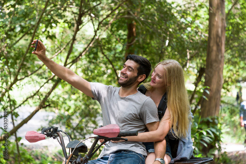 Young man and woman driving off road adventure with happy and smiling. Couple riding on ATV bike or quad bike on road along forest trail on mountain. Camping, jungle adventure concept