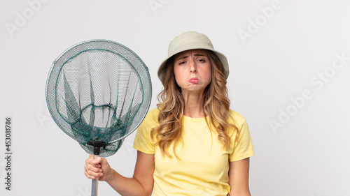 pretty thin woman feeling sad and whiney with an unhappy look and crying wearing hat and holding a fish net photo