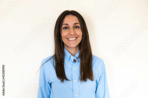Obraz na płótnie Young and attractive woman looking corporative with a shirt smiling at the camera, looking professional and ready to do bussiness with a white background. Wearing a blue shirt. Latin woman business. w salonie