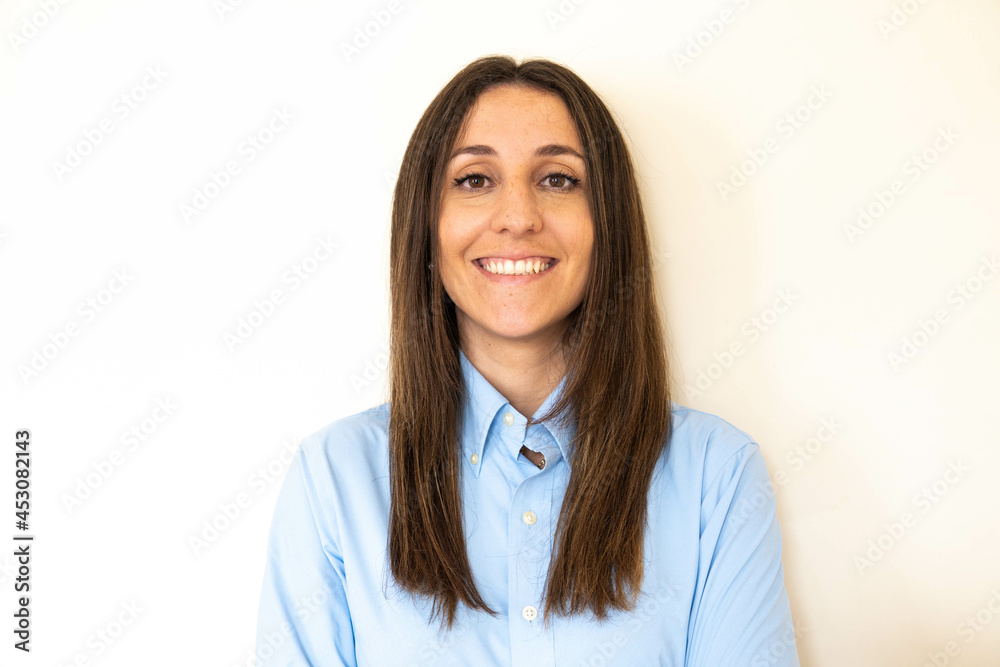 Young and attractive woman looking corporative with a shirt smiling at the camera, looking professional and ready to do bussiness with a white background. Wearing a blue shirt. Latin woman business.
