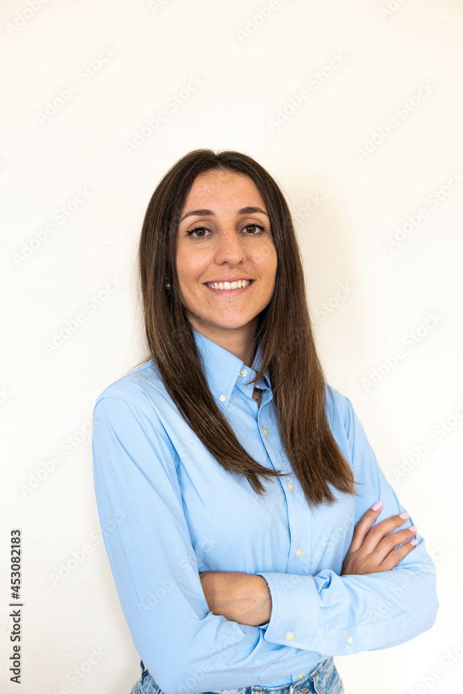 Young and attractive woman looking corporative with a shirt smiling at the camera, looking professional and ready to do bussiness with a white background. Wearing a blue shirt. Latin woman business. Young and attractive woman looking corporative with a shirt smiling at the camera, looking professional and ready to do bussiness with a white background. Wearing a blue shirt. Latin woman business.