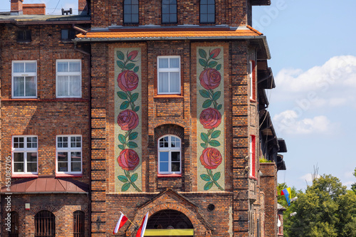 Rose pattern mosaic on facade of a red brick building at Liberation Square in the area of historic housing estate for coal miners, Katowice, Nikiszowiec, Poland