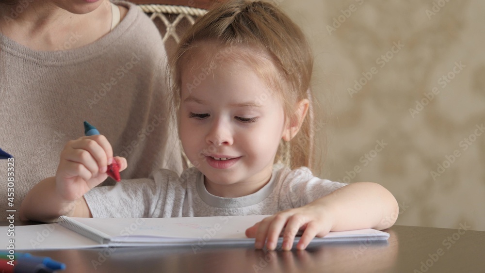 Mom, child, daughter together draw child's drawing at home. Little girl