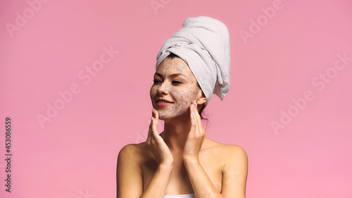 Wallpaper Mural joyful woman with towel on head applying face mask while looking away isolated on pink Torontodigital.ca