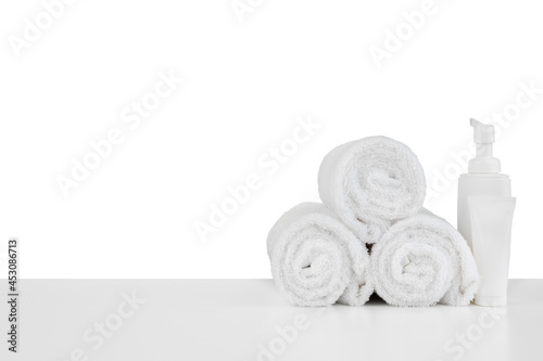 Composition of cosmetic bottles and towels isolated on white