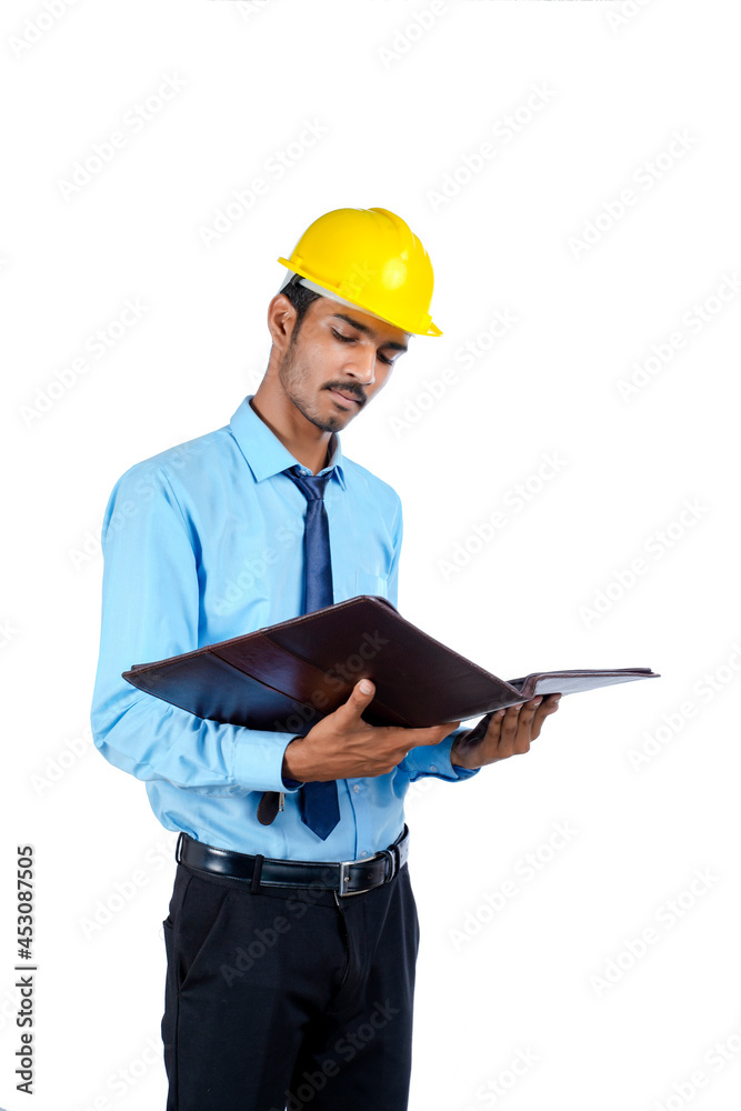 Young Indian male engineer wearing yellow color hard hat on white background. Young Indian male engineer wearing yellow color hard hat on white background.