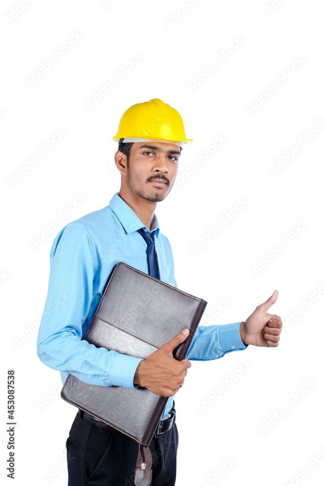 Young Indian male engineer wearing yellow color hard hat on white background. Young Indian male engineer wearing yellow color hard hat on white background.