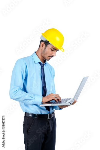 young Indian engineer in uniform and using laptop on white background.