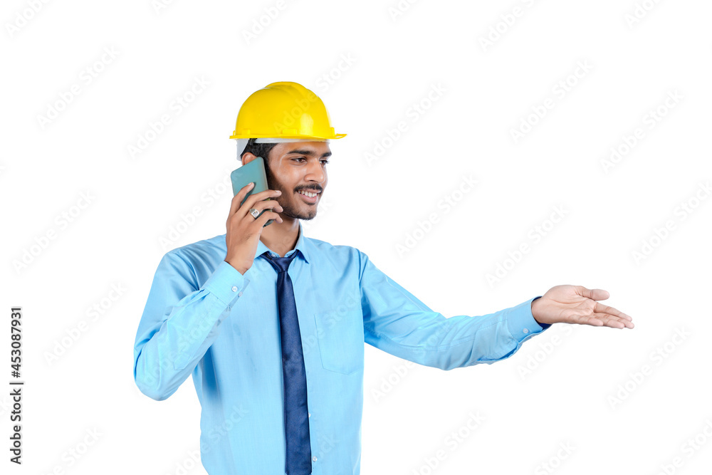 Young indian engineer or construction site worker using smartphone.