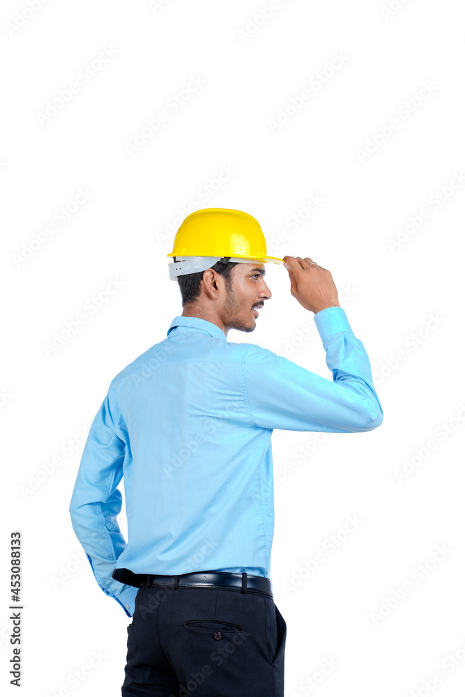 Young Indian male engineer wearing yellow color hard hat on white background.