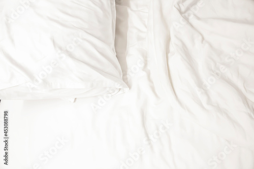 Fototapeta Naklejka Na Ścianę i Meble -  white pillow with messy messy blanket on bed in bedroom Close up of bedding sheets with copy space.