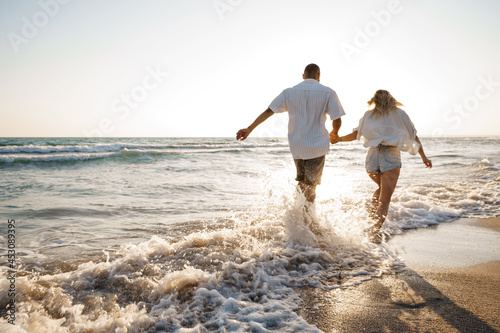 Cuadro en lienzo Young beautiful couple walking on beach near sea