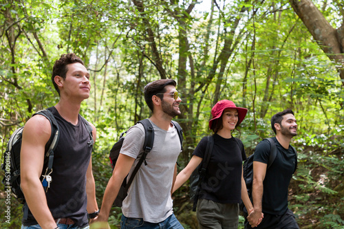 Group of male and woman backpackers hikers hiking with backpacks walking on road along forest trial. Camping, jungle adventure concept
