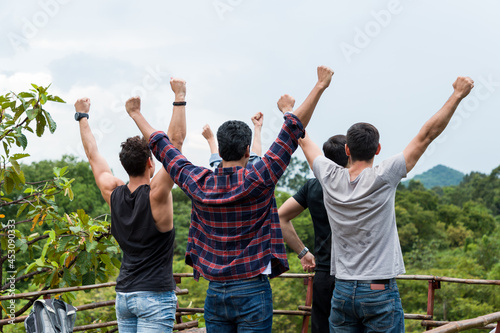 Group of male hiking and camping. Back view of group of young tourists man camping standing raising up his hands on mountain