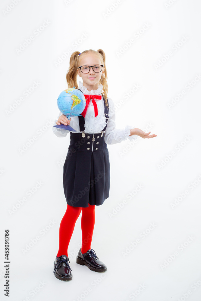 a little schoolgirl girl in a school uniform holds a globe isolated on a white background