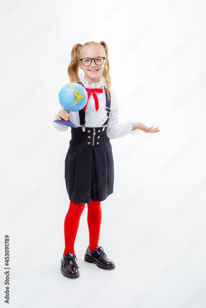 a little schoolgirl girl in a school uniform holds a globe isolated on a white background