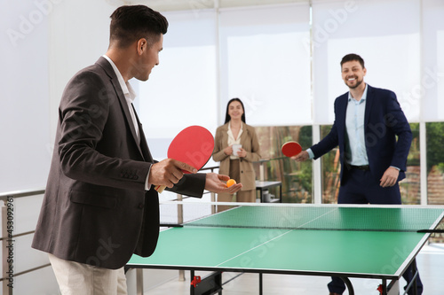 Business people playing ping pong in office