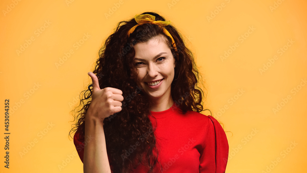 happy brunette woman looking at camera and showing thumb up isolated on orange happy brunette woman looking at camera and showing thumb up isolated on orange