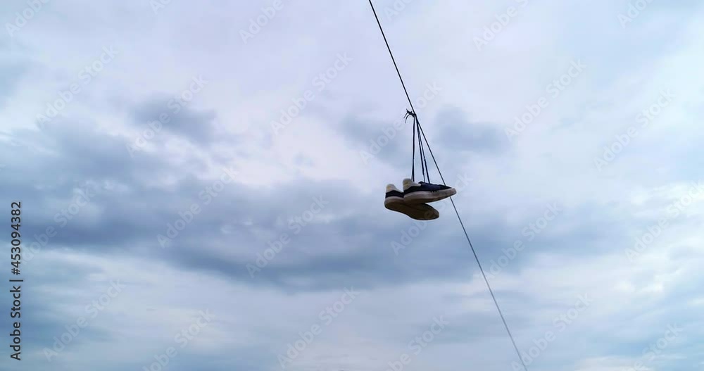 Aerial: Panning Descending Pair Of Shoes Hanging On Electric Wire Against Cloudy Sky - Erfurt, Germany Aerial: Panning Descending Pair Of Shoes Hanging On Electric Wire Against Cloudy Sky - Erfurt, Germany