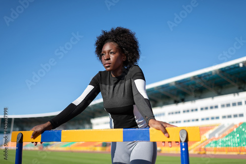 African American sportswoman resting near hurdle photo