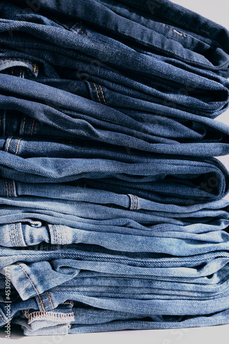 a pile of blue jeans on a grey background. Close up